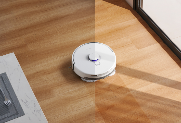 Narwal Freo Z Ultra robot vacuum on wooden floor, showing a clean section versus a dirty section.